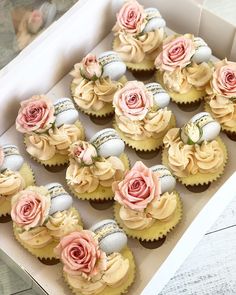 cupcakes decorated with pink and white flowers in a box