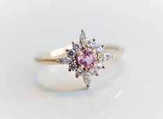 Skylar - Pink Sapphire solid 14k gold with 0.2 ct Diamond, White Sapphire or CZ, Pink Sapphire Halo Cluster Ring, Sapphire Engagement Ring by EmiConnerJewelry on Etsy https://www.etsy.com/listing/607513019/skylar-pink-sapphire-solid-14k-gold-with Pink Brilliant Cut Cluster Ring For Wedding, Wedding Pink Sapphire Ring With Halo Design, Pink Round Cluster Ring With Halo Setting, Pink Sapphire Ring With Halo, Pink Cluster Ring With Center Stone For Wedding, Pink Cluster Ring With Brilliant Cut, Pink Round Cut Cluster Ring Fine Jewelry, Pink Round Cluster Ring In Fine Jewelry Style, Heirloom Pink Sapphire Ring For Wedding