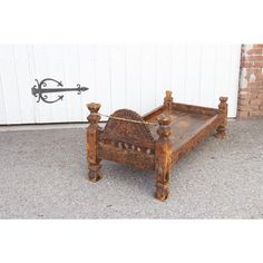 an old wooden bed frame sitting on top of a cement floor next to a white wall