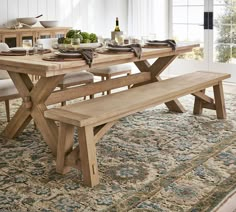 a wooden table with two benches in front of it and a rug on the floor