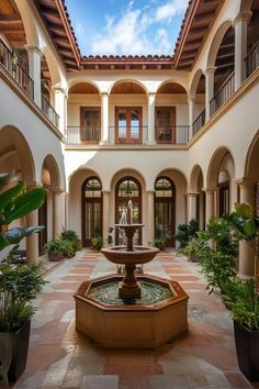 an indoor courtyard with a fountain and potted plants in the center, surrounded by arches