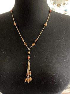 Vintage brown orange amber glass beaded gold tone lariat drop chain tassel necklace 57cm long I think hook clasp is replacement Orange Faceted Beads Jewelry, Orange Beaded Dangle Necklaces, Bohemian Drop Necklace With Beaded Chain, Vintage Brown Jewelry With Adjustable Chain, Brown Metal Dangle Necklaces, Elegant Amber Beaded Chain Necklace, Elegant Orange Jewelry With Faceted Beads, Elegant Amber Necklace With Gold Beads, Elegant Amber Necklace With Beaded Chain