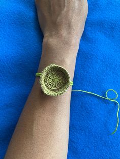 a woman's arm with a green bracelet on it and a string attached to the wrist