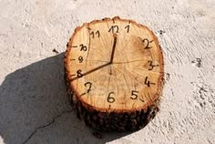 a clock made out of a tree stump on the ground with numbers painted on it