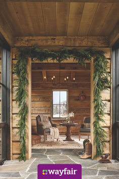 the front door to a log cabin with greenery on it and an open fire place