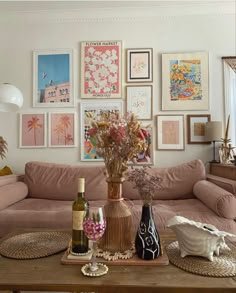 a living room with pink couches and pictures on the wall above it, along with vases filled with flowers