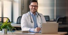 a man in a lab coat sitting at a desk with a laptop