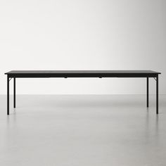 a black table sitting on top of a white floor in front of a gray wall