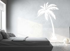 a bed sitting under a palm tree next to a window