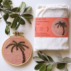 a cross stitch palm tree on a white background next to a pair of scissors and some green leaves