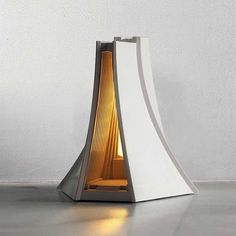 a lamp that is sitting on the floor next to a white wall with light coming from it