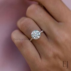 a woman's hand with a diamond ring on top of her finger and an engagement band