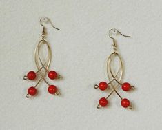 two pairs of earrings with red beads hanging from them