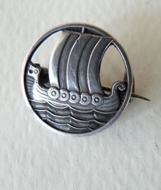 a silver pin with a boat on it