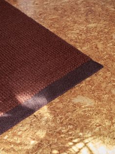 a brown rug sitting on top of a wooden floor next to a white and black cat