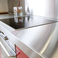 a stove top oven sitting inside of a kitchen next to a glass filled with water