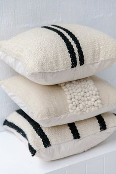 three pillows stacked on top of each other in front of a white wall with black stripes