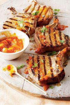 grilled pork chops with dipping sauce on a cutting board