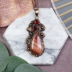 Introducing our stunning copper pendant, a unique piece that effortlessly blends elegance with rustic charm. Handcrafted with meticulous attention to detail, this pendant showcases the enchanting beauty of copper, known for its warm and earthy tones. At the heart of this captivating pendant lies a mesmerizing jasper gemstone, carefully chosen for its striking patterns and vibrant earthly hues. Each jasper gemstone is truly one-of-a-kind, making this pendant a true statement piece for any wardrobe. To add an extra touch of allure, a rich garnet gemstone dangles delicately from the bottom, complementing the rich copper tones and enhancing the pendant's overall beauty. Skillfully designed, this pendant captures the essence of nature's artistry, effortlessly blending the rugged charm of copper Jasper Jewelry, Copper Wire Jewelry, Natural Stones Necklace, Jasper Necklace, Garnet Necklace, Unique Gifts For Women, Garnet Jewelry, Jasper Pendant, Handmade Copper