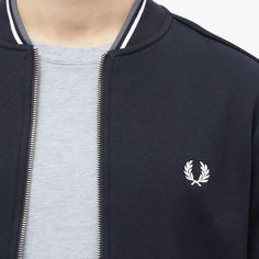 This season sees Fred Perry lend its iconic twin tipping to the collar of this tennis bomber. In slick black, it’s crafted from a soft cotton-poly blend and retains all of the style’s trademarks, including: a zip closure and chunky ribbing. Infused with sporting influence, it’s completed at the chest with the brand’s signature laurel wreath..79% Cotton, 21% Polyester.Zip Closure.2 Side Pockets.Embroidered Branding.Ribbed Trims.Model is 6ft 1in/1.86m with a 35”/89cm chest and is wearing a size Medium. Casual Varsity Jacket With Logo And Baseball Collar, Casual Varsity Jacket With Embroidered Logo For Spring, Classic Varsity Jacket With Embroidered Logo For Streetwear, Casual Winter Varsity Jacket With Logo Detail, Casual Outerwear With Logo And Baseball Collar, Classic Streetwear Track Jacket With Ribbed Cuffs, Classic Track Jacket With Ribbed Cuffs For Streetwear, Classic Black Varsity Jacket With Ribbed Collar, Casual Track Jacket With Embroidered Logo For Fall