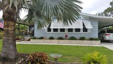 a car parked in front of a house next to a palm tree and flower bed