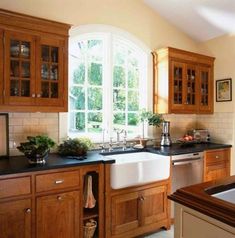 a kitchen with wooden cabinets and black counter tops, along with a large window over the sink