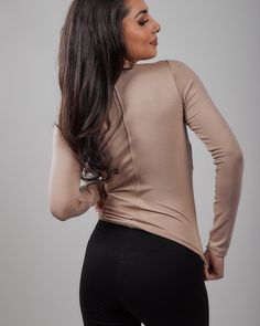 a woman with her back to the camera wearing black leggings and a tan top