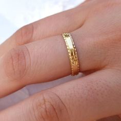 a close up of a person's hand with a gold ring on their finger