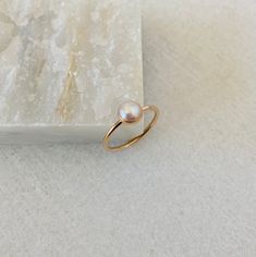 This dainty pearl ring will be handmade to order in your size.  Created with a natural 6mm white freshwater pearl, it will make a beautiful birthday gift for a July born person.  Please select the material and band width at the checkout. *Listing is for a pearl ring only. *Every pearl is unique but will closely match the featured one.  Model wears ring size 5, 1.3mm band Minimalist Pearl Drop Ring For Wedding, Minimalist Wedding Pearl Ring With Pearl Drop, Minimalist Pearl Drop Ring For Anniversary, Simple Pearl Ring For Wedding, Minimalist Pearl Drop Ring For Gift, Dainty Pearl White Ring For Anniversary, Minimalist Pearl Rings With Pearl Charm, 14k Yellow Gold Rings With Pearl Charm, Minimalist Pearl Drop Ring For Promise