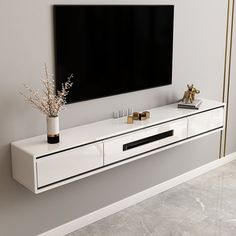 a white entertainment center with gold trimmings and a black television mounted on the wall