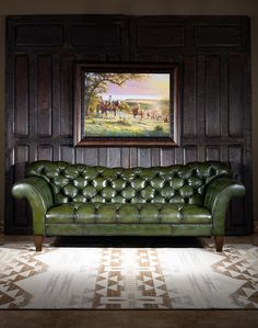 a green leather couch sitting in front of a painting