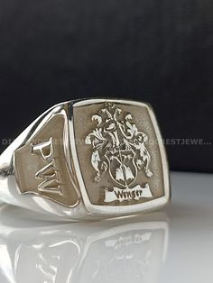 a signet ring with the coat of arms and initials on it, sitting on a white surface