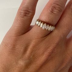 a woman's hand wearing a gold ring with five stones on the middle finger