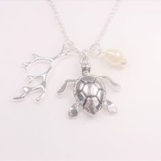 a silver turtle and pearl necklace on a white background with the sea animal charm attached to it's neck