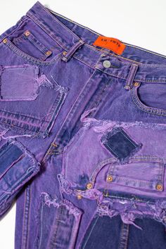 purple jeans with holes and orange tags on them are sitting next to each other in front of a white background