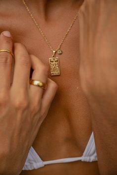 a woman wearing a gold necklace and ring holding onto her chest with the letter f on it