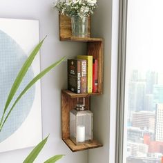 two wooden shelves with books and flowers on them in front of a window overlooking the city