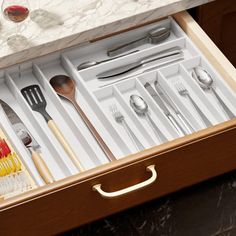 an open drawer with utensils and silverware in it on a marble countertop