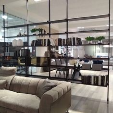 a living room filled with furniture and bookshelves in front of a glass wall