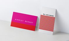 two business cards sitting next to each other on a white counter top with red and pink stripes