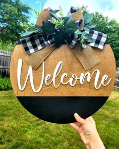 a hand holding up a welcome sign in the grass