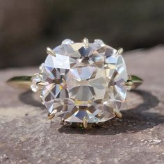 an oval cut diamond ring sitting on top of a rock