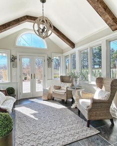 a living room with two chairs and a rug on the floor in front of windows