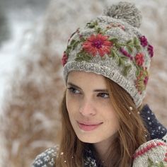 a woman wearing a knitted hat with pom poms on it's brim