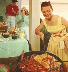 a woman in a yellow dress is grilling hot dogs and other foods on a table