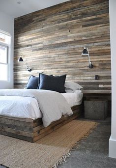 a large bed sitting next to a window in a bedroom under a wooden headboard