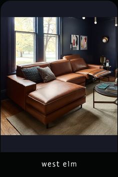 a large brown leather couch sitting in front of a window