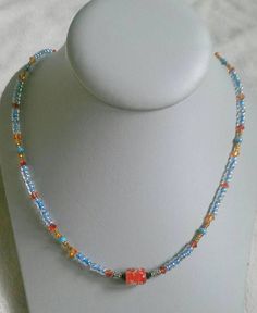 Red/orange bicone crystal beads, blue seed beads, brown seed beads, and a speckled red glass bead in the middle. Toggle clasp. Measures 19.5 inches long end to end. Adjustable Orange Beaded Necklaces With Heart Beads, Adjustable Orange Beaded Necklace With Heart Beads, Orange Beaded Necklaces With Czech Glass, Orange Beaded Glass Necklaces, Orange Glass Beaded Necklace With Colorful Beads, Orange Czech Glass Beaded Necklaces, Orange Czech Glass Beaded Necklace, Crystal Beaded Necklace, Crystal Bead Necklace