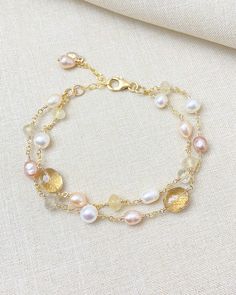 Fall in love with this layered gold bracelet, featuring a stunning combination of pale pink and golden gemstones intricately paired with luminous freshwater pearls. Meticulously handcrafted, this luxe and sophisticated piece is designed to elevate any outfit, whether you're dressing up for a special occasion or adding a touch of elegance to your everyday wear. The seamless interplay of colors and textures creates a visually captivating accessory that truly stands out. Each strand of this layered Feminine Gold Jewelry With Round Beads, Feminine Gold Round Beaded Jewelry, Feminine Gold Bracelet With Pearl Charm, Feminine Gold Bracelets With Pearl Charm, Elegant Double Strand Natural Stones Bracelets, Handmade Gold Feminine Bracelets, Pearl Bracelet With Natural Stones For Wedding, Delicate Gold Bracelets With Pearl Charm, Handmade Feminine Gold Bracelets