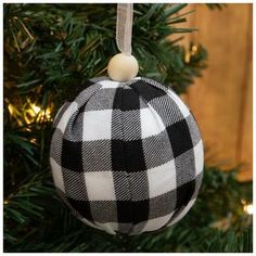 a black and white plaid ball ornament hanging from a christmas tree with lights in the background